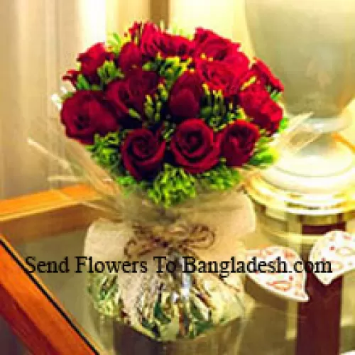 12 roses rouges avec quelques fougères dans un vase